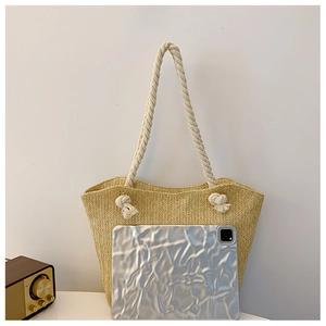 Detail of straw tote bag with woven texture and white cotton rope handles next to a tablet