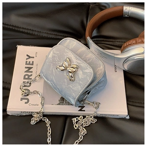 Vue détaillée du mini sac bandoulière bleu clair texturé avec boucle papillon argent