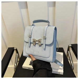 Détail du sac à dos bleu clair avec nœud argenté et poignée supérieure robuste