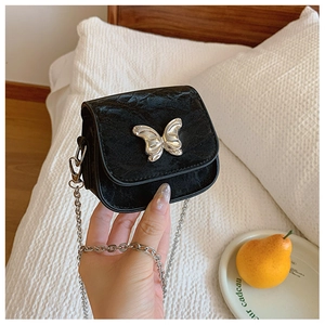 Détail du petit sac en velours noir avec fermoir papillon argenté et bandoulière