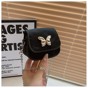 Détail d'un mini sac bandoulière noir avec breloque papillon et bandoulière en chaîne