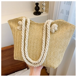 Detailed close-up of woven herringbone straw tote bag with white cotton rope handles