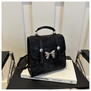 Détail d'un mini sac à dos en suédine noire avec nœud argenté et poignée de transport