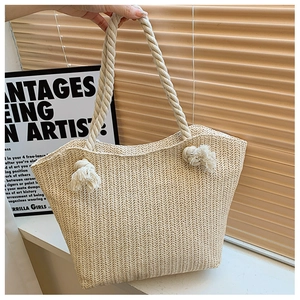 Close-up of beige woven straw tote bag featuring thick rope handles and herringbone pattern