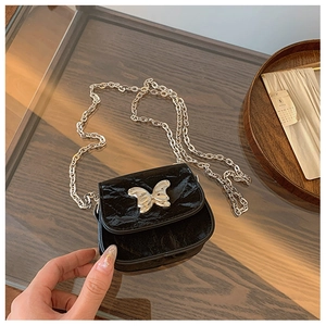 Détail du fermoir papillon argenté et du cuir brillant texturé du mini sac à chaîne
