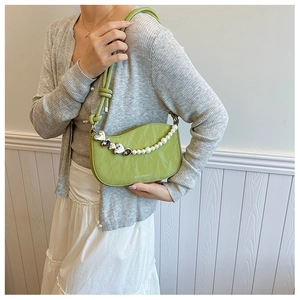Detail of green pleated hobo bag with heart charm, pearl chain and fashion text