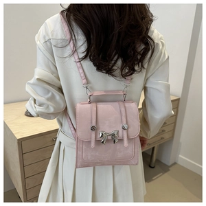 Détail du sac seau rose en suédine avec nœud argenté sur un trench-coat beige