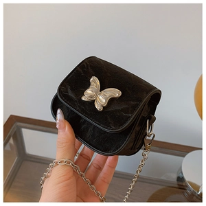 Gros plan d'un mini sac à chaîne en velours noir avec une grande boucle papillon en métal argenté