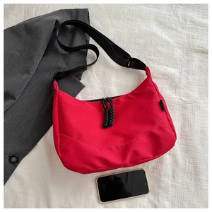 Detailed top view of red nylon tote bag featuring durable black zippers and wide strap