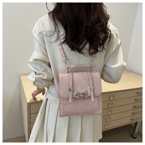 Vue détaillée du mini sac à dos rose avec fermoir papillon argenté sur une robe