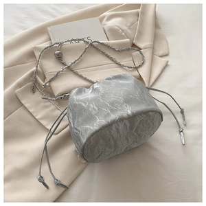 Détail du sac seau plissé argenté avec cordon de serrage et bandoulière en chaîne