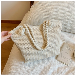 Detail of the woven straw tote bag with V-shaped texture and thick cotton rope handles