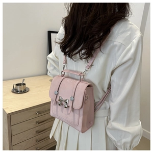 Vue latérale d'un mini sac à dos rose avec nœud argenté et lanières en cuir