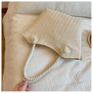 Detail of herringbone weave texture and rope handles on a beige straw tote bag