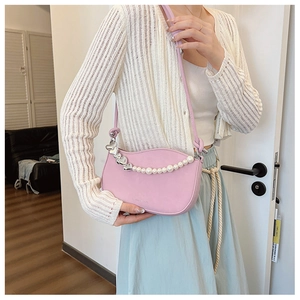 Detail of light pink half-moon bag with pearl chain and silver heart pendant decoration