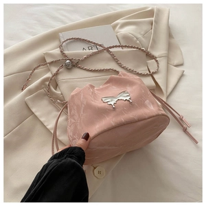 Détail du sac seau rose brillant avec nœud métallique argenté et bandoulière tressée