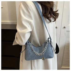 Detail of light blue denim crescent bag with chunky silver chain and round pendant
