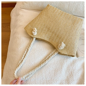 Detail of straw woven tote with thick cotton rope handles and rustic knot design