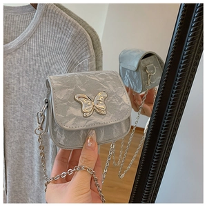 Détail du sac à chaîne argenté avec texture marbrée et ornement papillon en métal