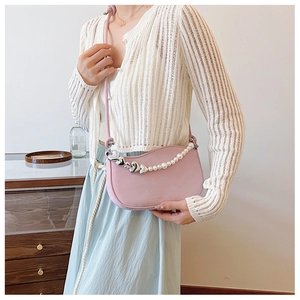 Detail view of pink half-moon bag with silver heart buckle and pearl chain decoration