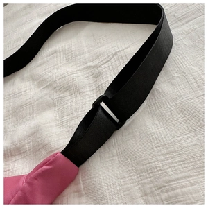Detailed close-up of the adjustable black nylon shoulder strap and pink fabric on tote bag
