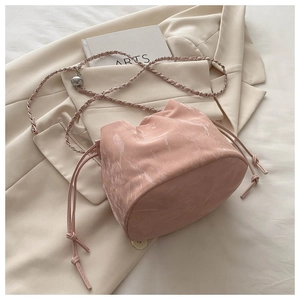 Détail du sac seau rose à motif marbré avec bandoulière chaîne sur blazer beige