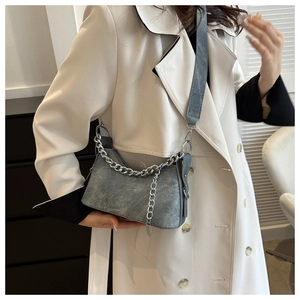 Detail of grey-blue textured shoulder bag with silver chain worn by a model