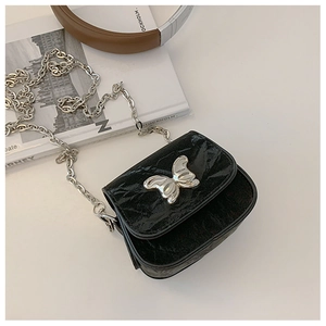 Détail du mini sac noir brillant plissé avec papillon en argent et bandoulière chaîne