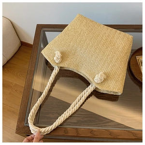 Detail of beige straw tote bag with braided texture and thick cotton rope handles