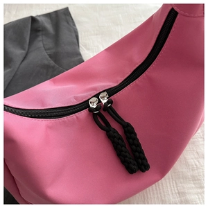 Detail of pink nylon tote featuring a sturdy black double zipper and woven rope pullers