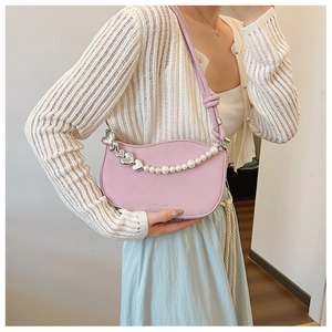 Detail of light purple underarm bag with pearl chain and heart metal charms on model