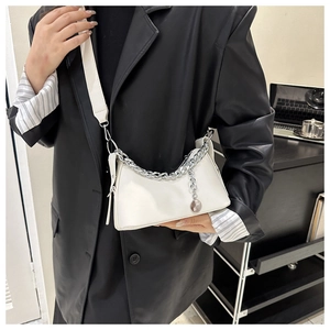 Detailed shot of white crescent shoulder bag with silver chunky chain on a leather jacket