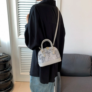 Detail of grey seashell crossbody bag with jacquard pattern and gold hardware