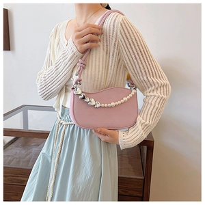 Detail of pink crescent bag with decorative pearl and silver heart chain strap