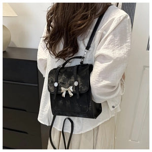 Vista detallada de una mini mochila negra con lazo plateado y correas ajustables