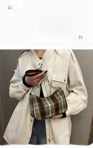 Detail of vintage plaid baguette bag with silver metal chain and brown leather handle