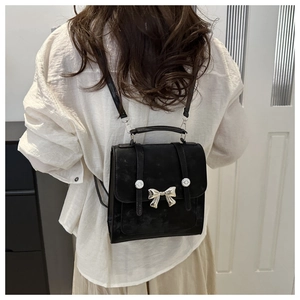 Vue détaillée du mini sac à dos noir à nœud papillon porté au dos montrant sa taille