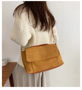 Sac bandoulière en daim marron porté à l'épaule pour le style et les dimensions