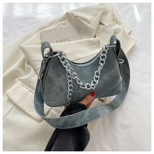 Detail of blue denim hobo bag featuring a bold silver chain and adjustable shoulder strap