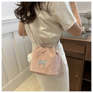 Détail du sac seau plissé rose avec papillon en métal argenté et bandoulière chaîne