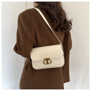 Détail du sac bandoulière élégant en cuir crème avec fermoir en métal doré sur modèle