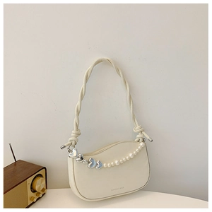 Close-up of cream underarm bag with pearl heart chain and fiber rope shoulder strap