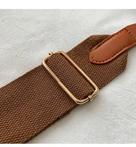 Détail de la bandoulière tissée marron réglable avec boucle dorée et coutures en cuir