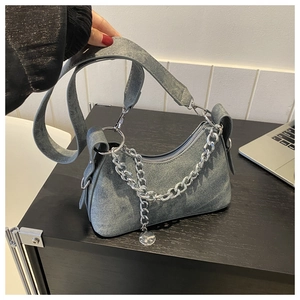 Detailed close-up of blue denim crescent bag with silver chain and metal zipper closure