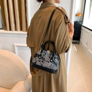 Minimalist black shell crossbody bag with white scroll pattern and gold hardware accents
