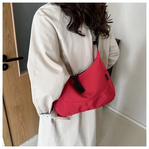 Detailed side view of a large red nylon crescent tote bag shown on model