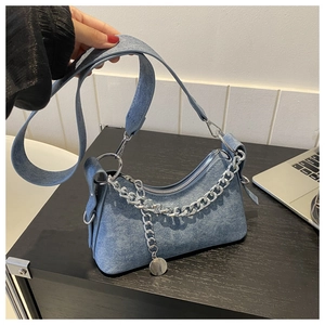 Macro detail of blue denim texture material and silver metal chain strap on crescent bag