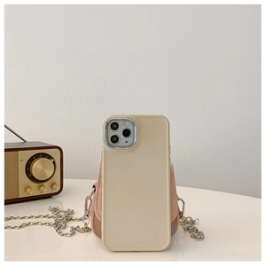 Détail de coque crème avec mini pochette rose et chaîne argentée sur une table