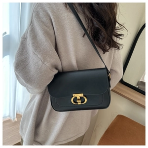 Détail du sac à rabat en cuir noir vintage avec un fermoir doré à double anneau