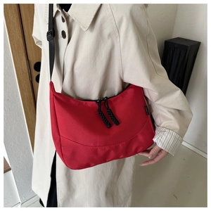 Detail of red nylon tote bag with black woven zippers and adjustable canvas shoulder strap